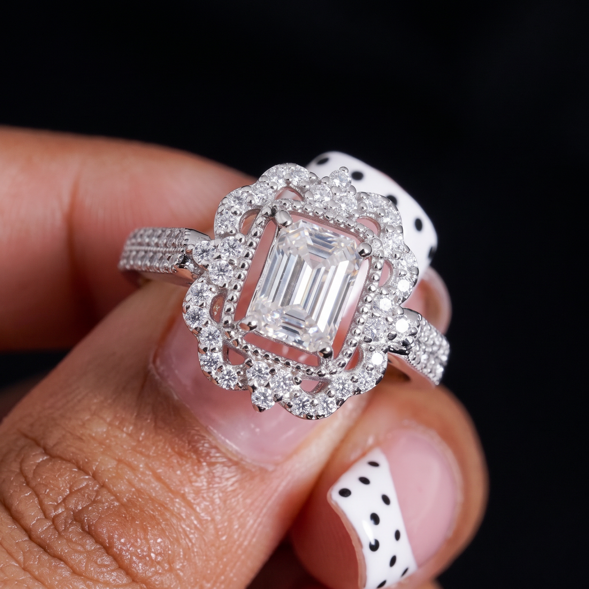 Emerald cut moissanite halo ring in hand, second angle