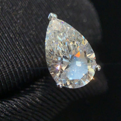 Single pear cut moissanite stud in detail, showing the point up prong setting and brilliant faceting