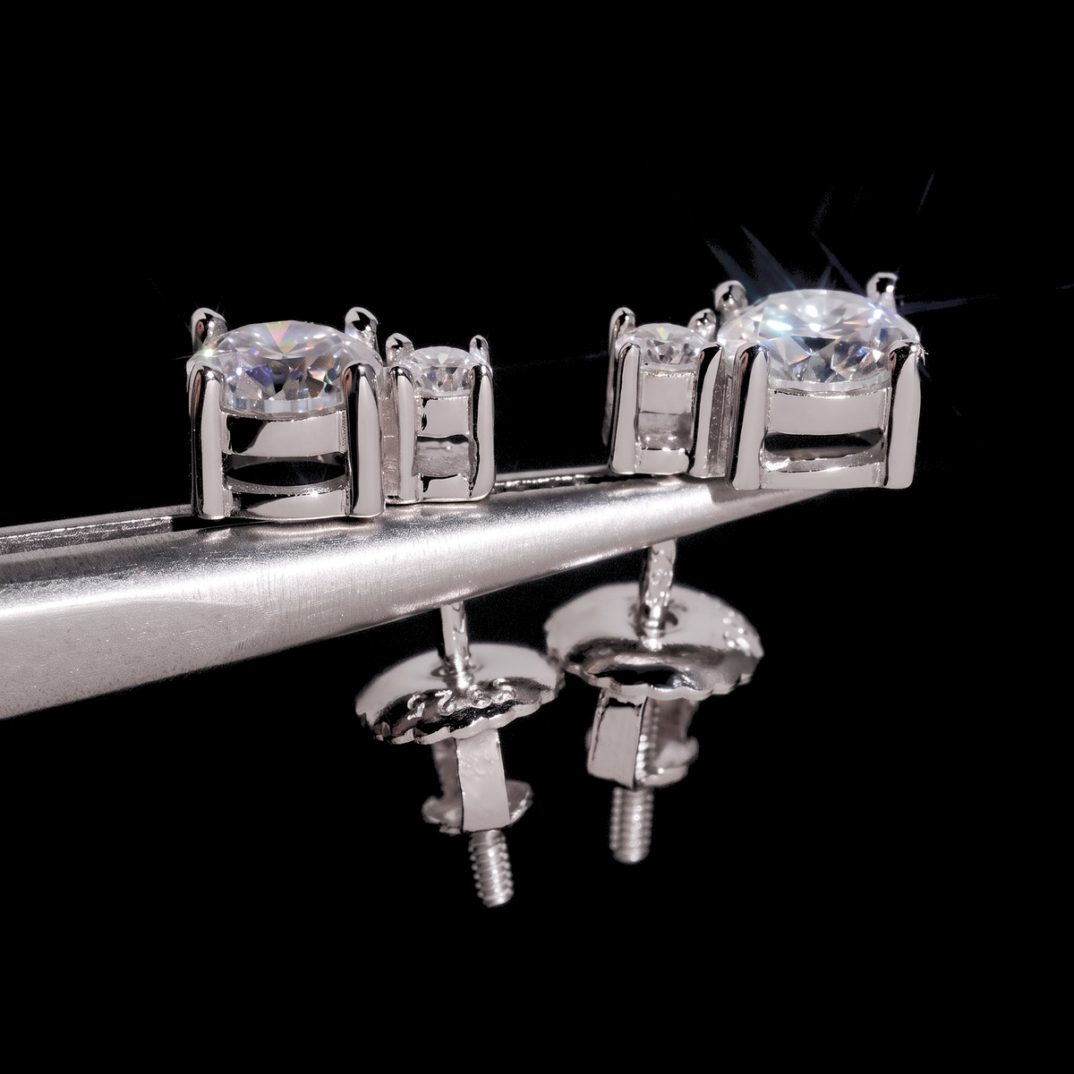 Two stone drop moissanite studs held on tweezers showing screw back posts