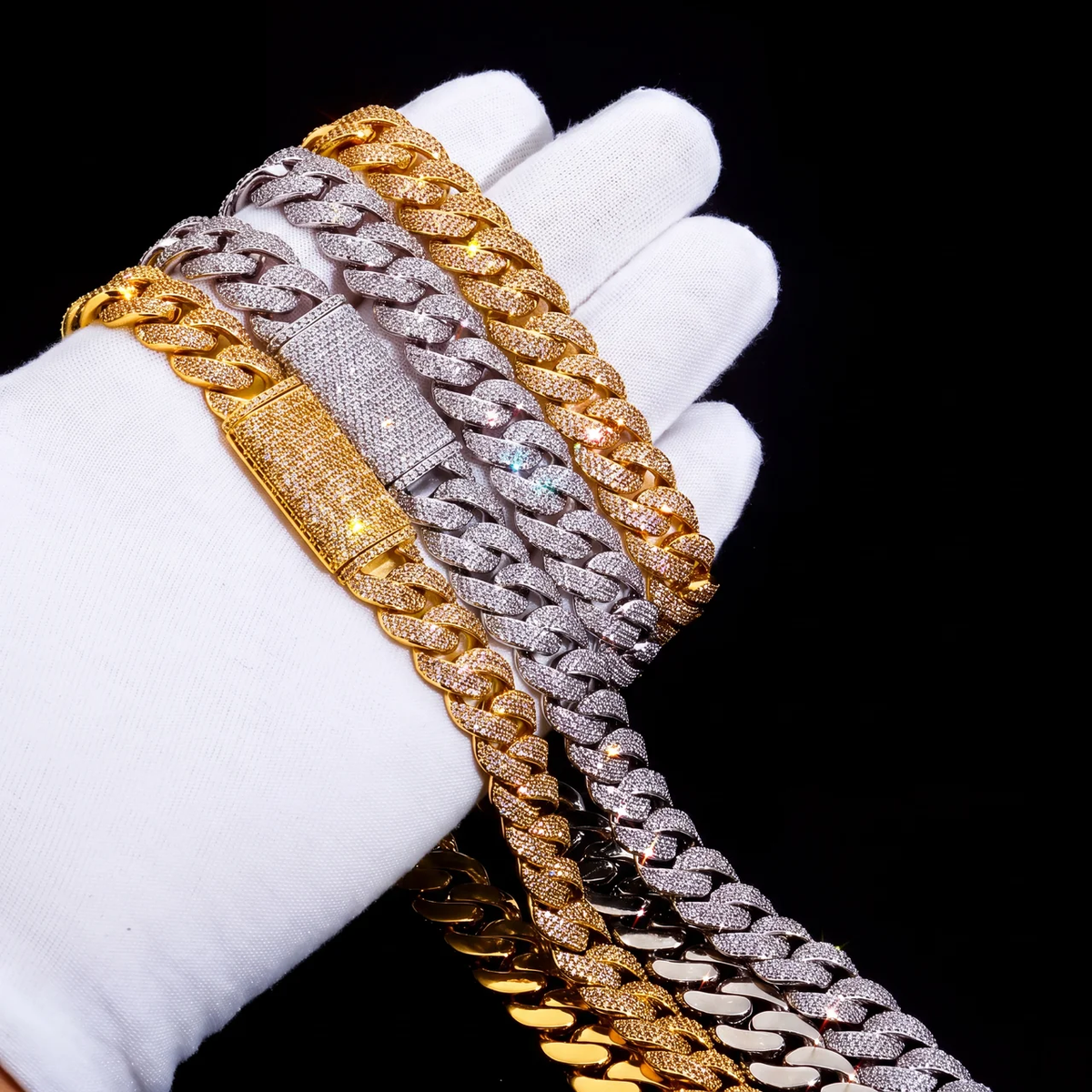 Stack of gold and silver micro pave cuban link chains and bracelets held in gloved hand