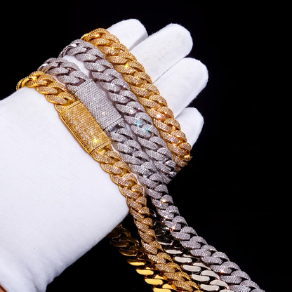 Stack of gold and silver micro pave cuban link chains and bracelets held in gloved hand