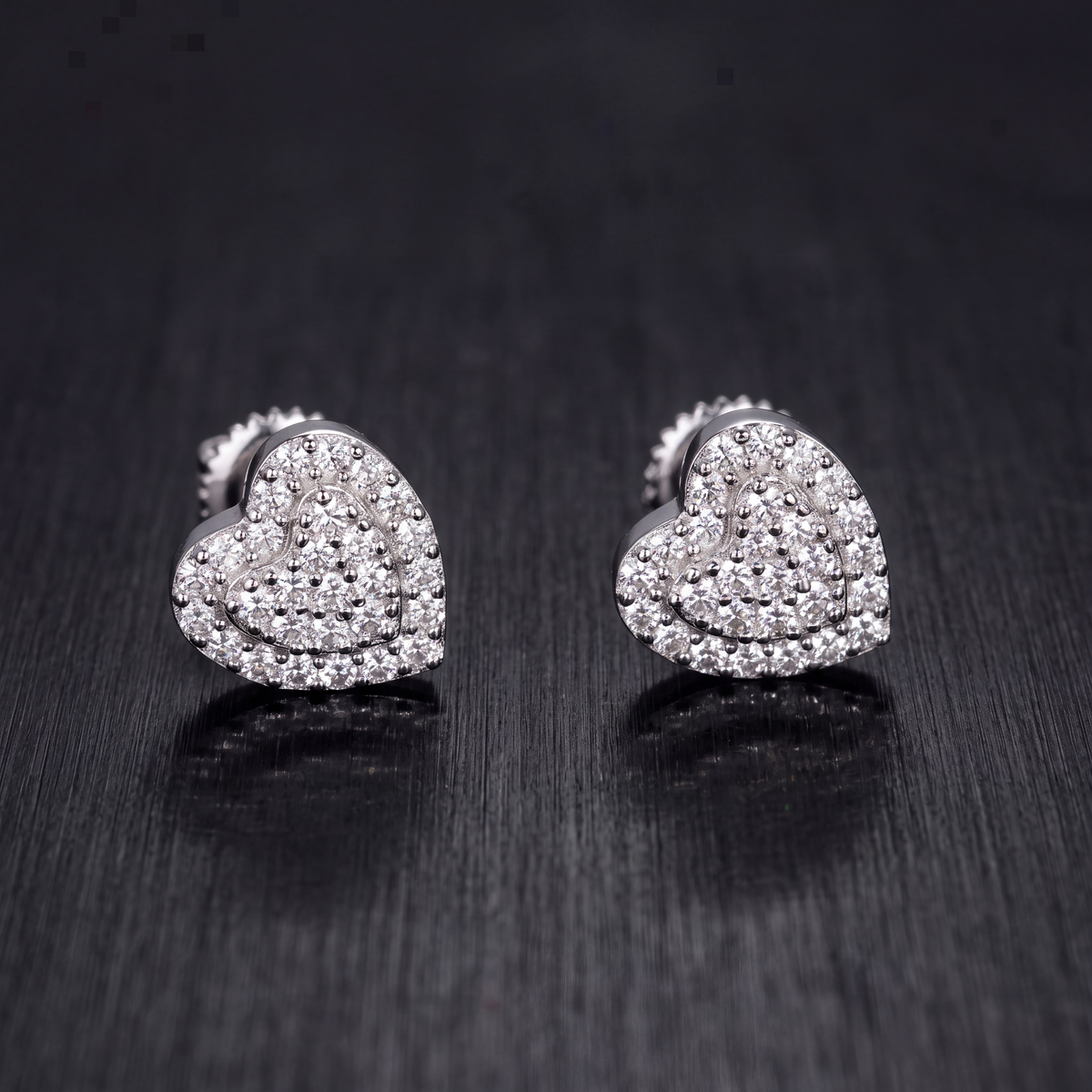 7.5mm moissanite heart stud earrings in 925 sterling silver on dark brushed metal